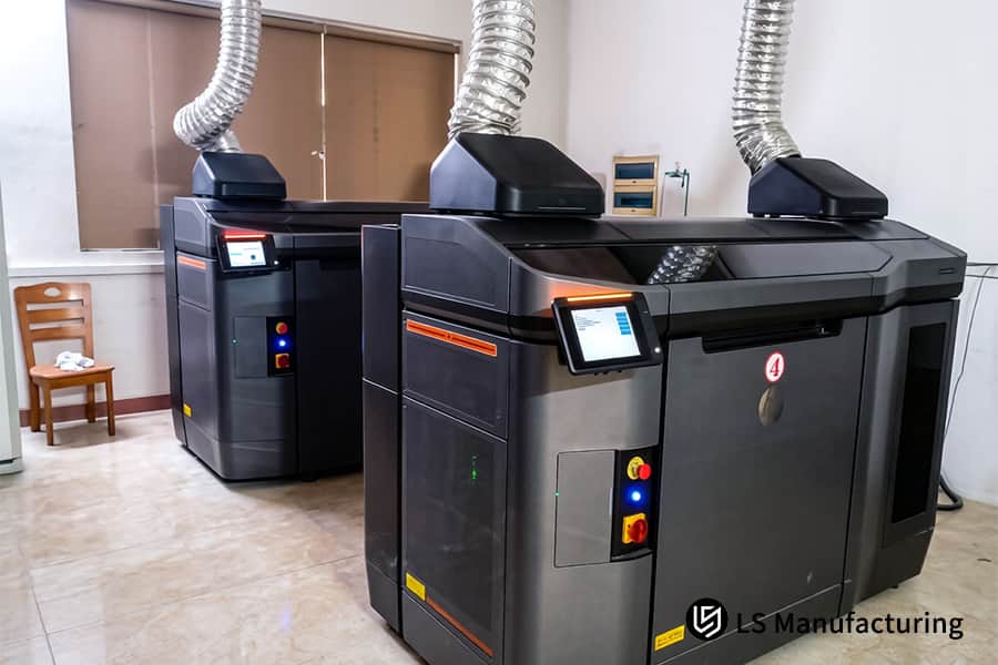 Una máquina de medición por coordenadas verifica las dimensiones de los soportes de nailon MJF impresos en 3D de color gris.