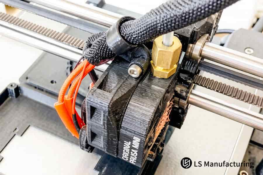 A 3D printer fabricates a black TPR custom pulley with an integrated gear mechanism.
