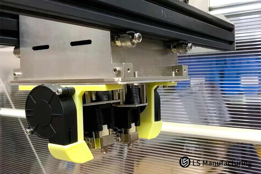 A 3D printer constructs a yellow TPU belt tensioner with a toothed drive mechanism.