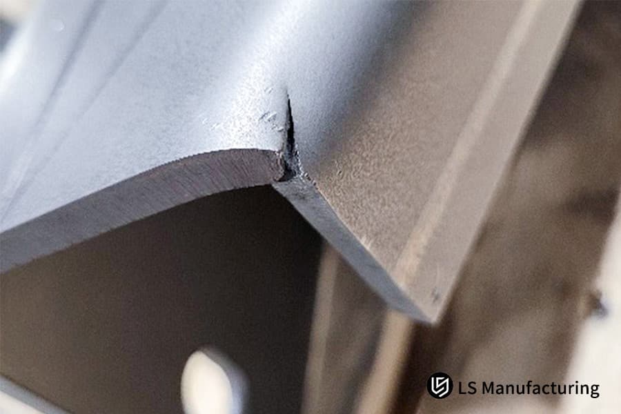 Fissure dans une tôle pliée due à un faible allongement.