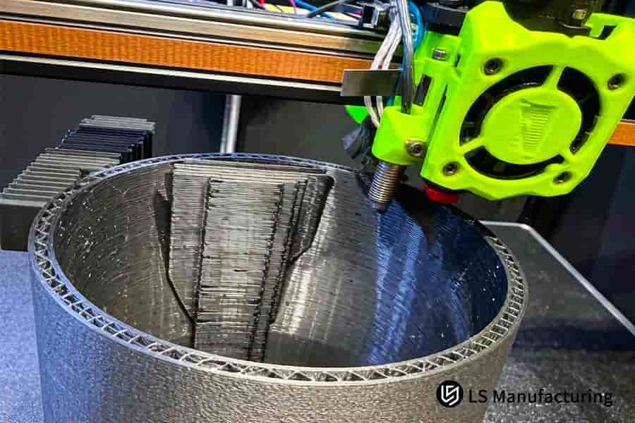 A print head deposits gray resin material to form a large cylindrical vessel on the printer bed.