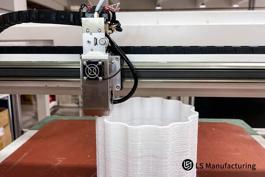 FDM 3D printing completes white plastic vase layer by layer in office environment.
