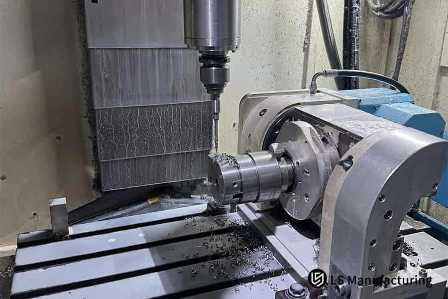 Une table rotative fait tourner une pièce métallique cylindrique sous une fraise, les copeaux tombant.
