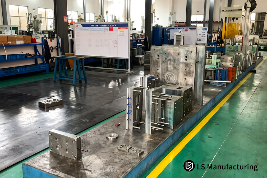Various tool steel mold components with blue markings await assembly on a factory workbench for a large project.