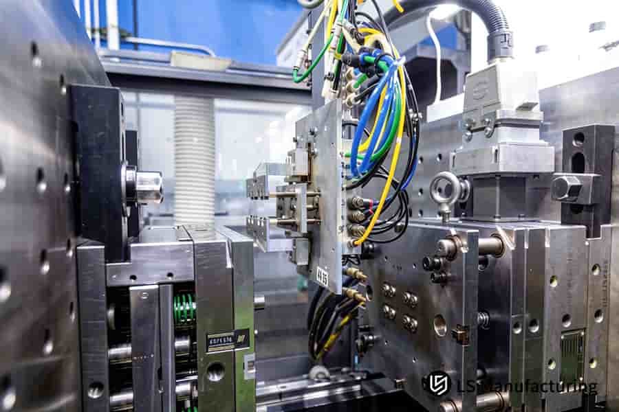 Custom tooling manufacturing involves a steel mold connected to colored hoses for cooling and hydraulic functions.