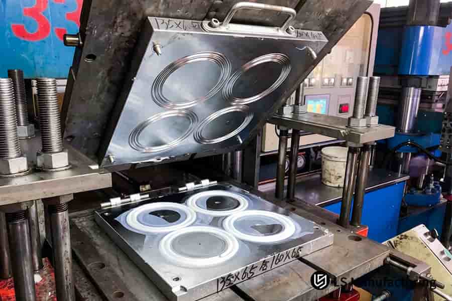 Rubber injection molding services compress white silicone rubber into circular seals for industrial machinery.