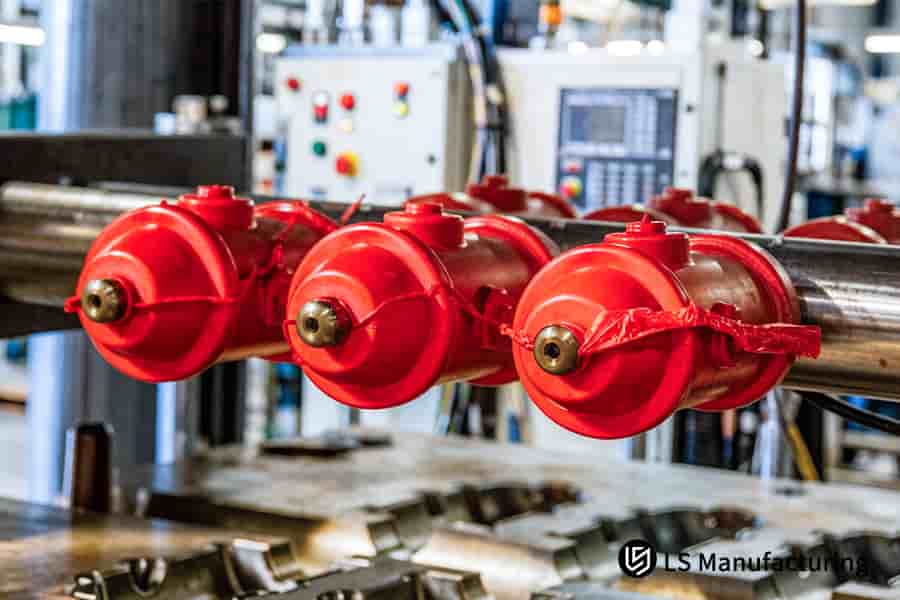 High-volume injection molding produces multiple red rubber seals on metal rods for automotive assemblies.