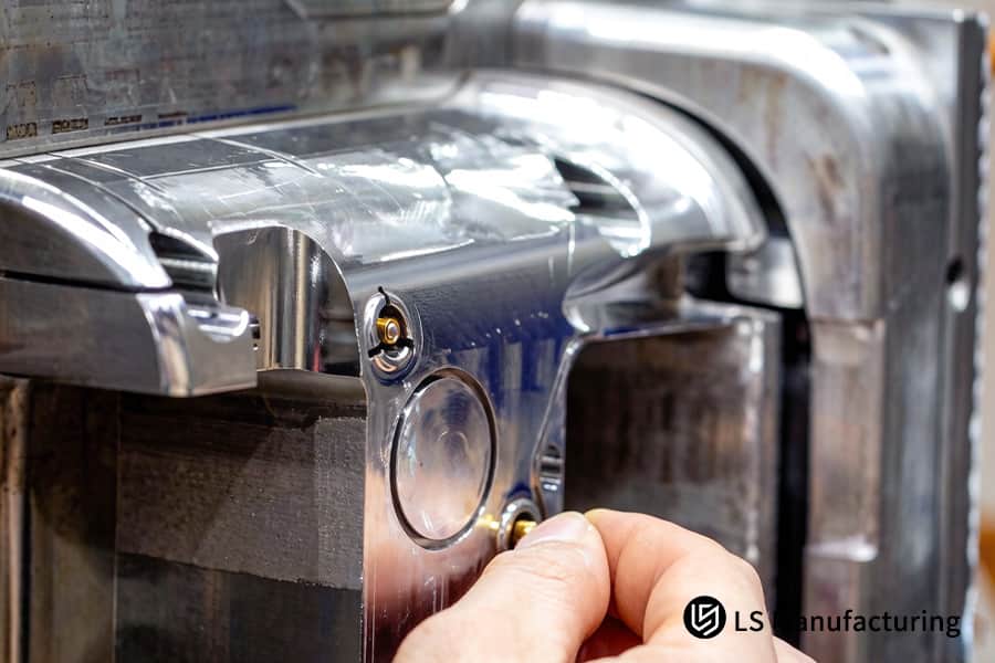 Un operaio regola uno stampo in acciaio inossidabile con inserti in ottone per una produzione di stampaggio a inserti economicamente vantaggiosa.