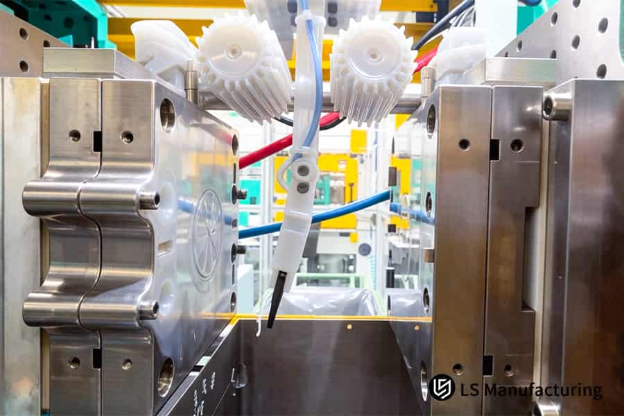A robotic arm transfers white silicone components attached to colored pneumatic hoses for assembly.