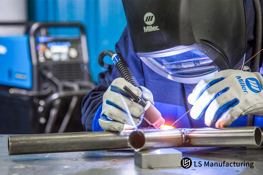 Um soldador funde tubos de aço inoxidável 304 com uma tocha TIG para manuseio de fluidos ou componentes do sistema estrutural.