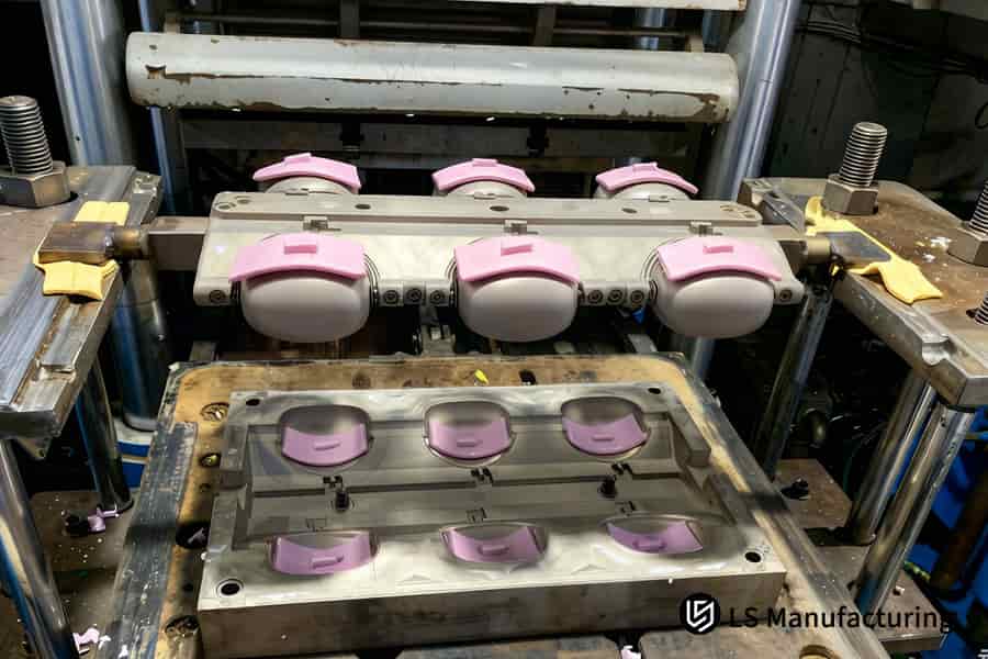 用于医疗部件的硅胶包覆成型工艺是将粉红色材料注入精密金属模具腔中。
