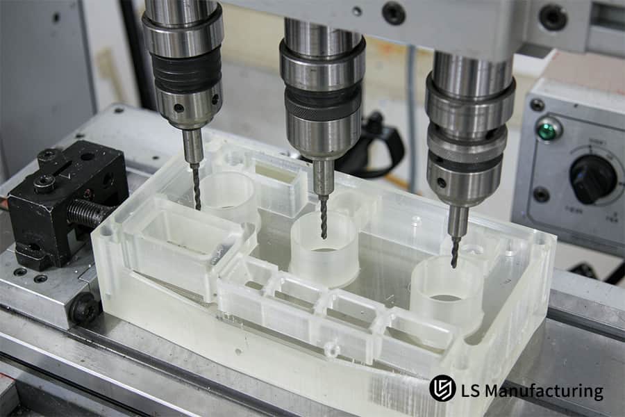 CNC machining opens 3x diameter holes in white connector box.