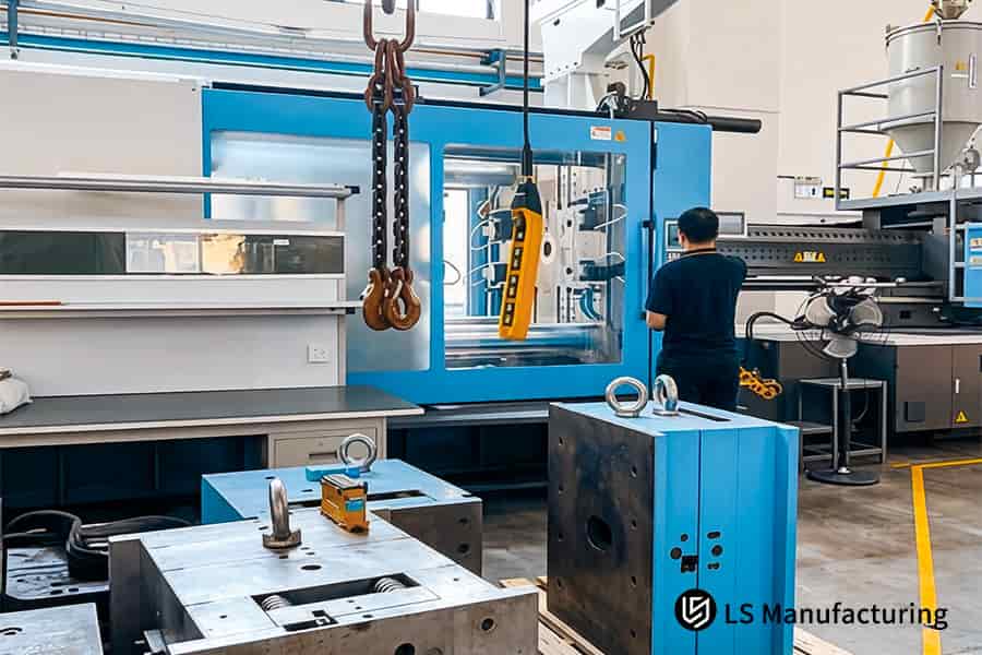 Un lavoratore aziona la macchina a iniezione per formare parti personalizzate dalla resina polimerica per vari settori.