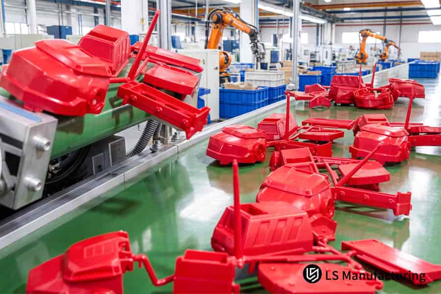 An automated conveyor carries newly molded red thermoplastic parts for inspection and packaging.