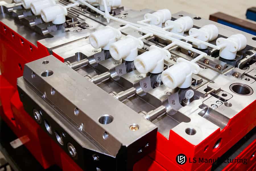 Precision nylon injection molding ejects white tubular parts from a multi-cavity steel mold for fluid systems.