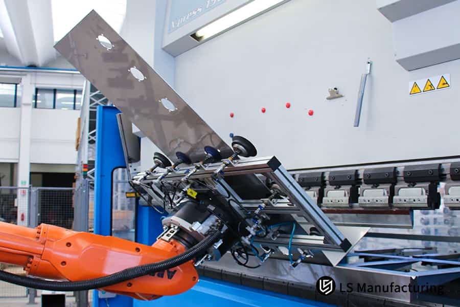 Robotic arm bending a metal sheet in a factory.