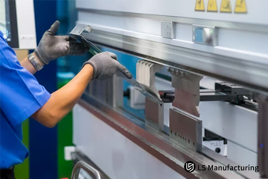 A worker operates a metal bending machine.