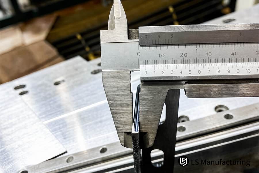 Il calibro di precisione misura la dimensione del bordo della lamiera di acciaio tagliata per la precisione della produzione.