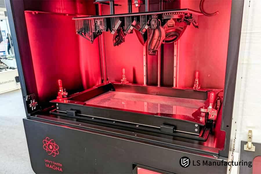La stampa 3D SLA abbassa la piattaforma di costruzione rossa nella vasca di resina fotosensibile liquida.
