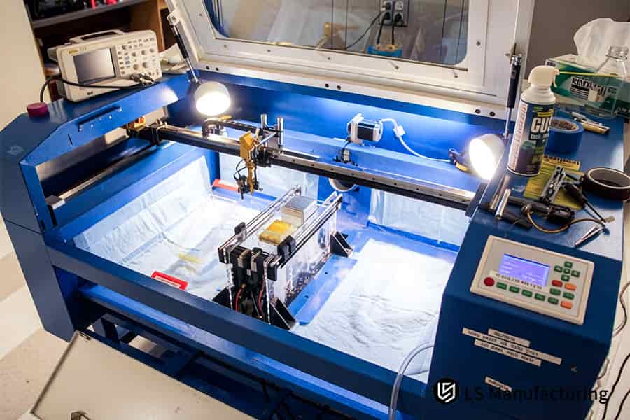 技術者は浸漬タンクを操作して、SLA 印刷部品から未硬化の樹脂を化学的に洗浄します。